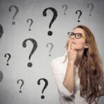 Woman with glasses pondering, surrounded by question marks, representing inquiries about Amazon DSP insurance coverage options.