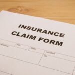 Insurance claim form on a wooden surface, relating to filing claims for Amazon DSP insurance.